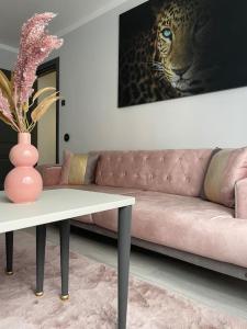 a living room with a pink couch and a table at Britannia ShortStay Apartment Caransebes in Caransebeş
