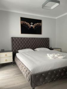 a bedroom with a large bed with a leather headboard at Britannia ShortStay Apartment Caransebes in Caransebeş