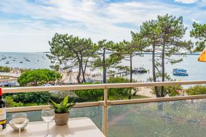 a balcony with wine glasses and a view of the beach at L'Embarcadère - Petit paradis 1ère ligne vue mer in Arcachon