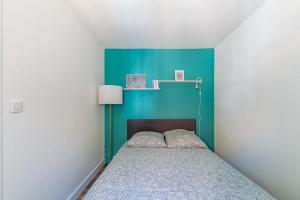 a small bedroom with a bed with a blue wall at Azul - Maison avec jardin à 200m de la plage in Courseulles-sur-Mer