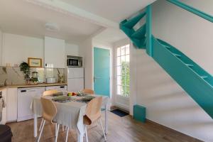 a kitchen with a table with chairs and a staircase at Azul - Maison avec jardin à 200m de la plage in Courseulles-sur-Mer