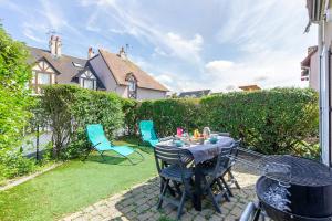 a patio with a table and chairs in a yard at Azul - Maison avec jardin à 200m de la plage in Courseulles-sur-Mer