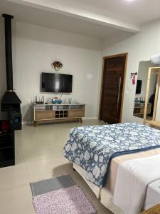 um quarto com uma cama e uma televisão de ecrã plano em Casa Copacabana 2 em Urubici
