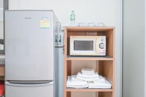 a refrigerator with a microwave and a shelf with towels at AC Habitat Bangkok in Bangkok