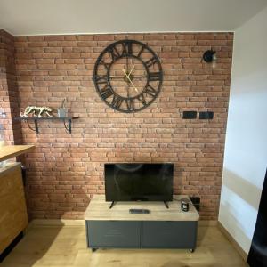 a large clock on a brick wall with a tv at Escale Studio Gonesse in Gonesse