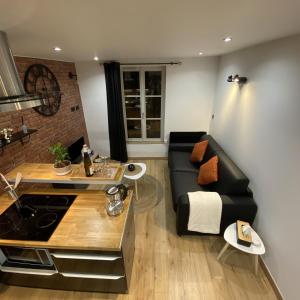 a living room with a black couch and a kitchen at Escale Studio Gonesse in Gonesse
