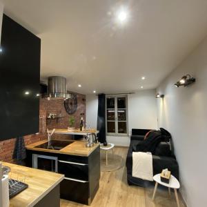 Escale Studio Gonesse في غونيس: غرفة معيشة مع أريكة سوداء ومطبخ