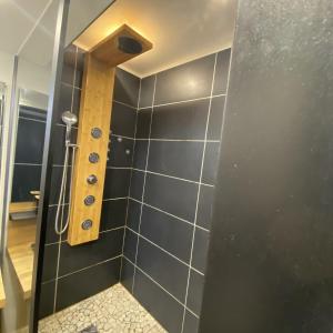 a bathroom with a shower with black tiles at Escale Studio Gonesse in Gonesse