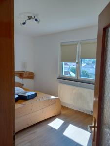 um quarto com uma cama de madeira e 2 janelas em Ferien im Brombachtal em Brombachtal