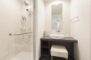 a white bathroom with a sink and a mirror at Tokyu Stay Shinjuku in Tokyo