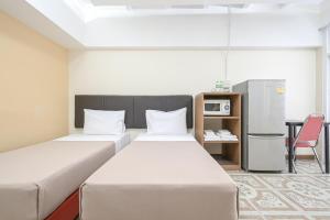 two beds in a room with a desk and a refrigerator at AC Habitat Bangkok in Bangkok