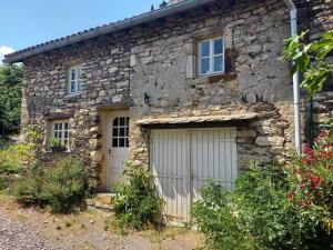 a stone house with two garage doors in front of it at MAISON ST LAURENT in Olargues