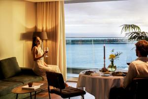 a woman sitting in a hotel room with a window at Octant Ponta Delgada in Ponta Delgada