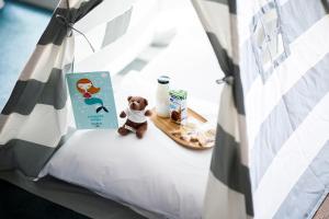a teddy bear sitting on a bed with a book at Octant Ponta Delgada in Ponta Delgada