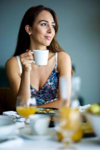 a woman sitting at a table with a cup of coffee at Octant Ponta Delgada in Ponta Delgada