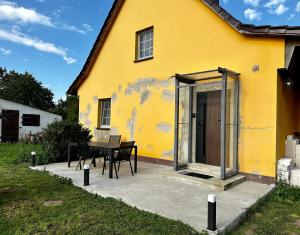 a yellow house with a table and chairs in front of it at Ka:Ma Hof Uckermark in Carmzow