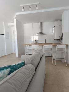 ein Wohnzimmer mit einem Sofa und einem Tisch sowie eine Küche in der Unterkunft SHERRY SUITES VIII Apartamentos PARKING GRATUITO in Jerez de la Frontera