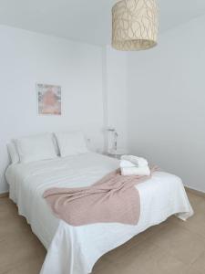 ein weißes Schlafzimmer mit einem Bett mit einer Decke darauf in der Unterkunft SHERRY SUITES VIII Apartamentos PARKING GRATUITO in Jerez de la Frontera