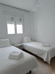 2 Betten in einem weißen Zimmer mit 2 Fenstern in der Unterkunft SHERRY SUITES VIII Apartamentos PARKING GRATUITO in Jerez de la Frontera