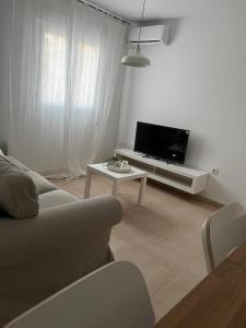 sala de estar con sofá, TV y mesa en SHERRY SUITES VIII Apartamentos PARKING GRATUITO, en Jerez de la Frontera