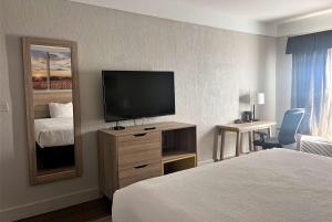 a hotel room with a bed and a flat screen tv at Days Inn by Wyndham Denham Springs-Baton Rouge East in Denham Springs
