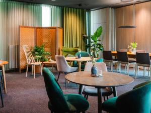 uma sala de espera com mesas, cadeiras e plantas em ibis Styles Nagold-Schwarzwald em Nagold