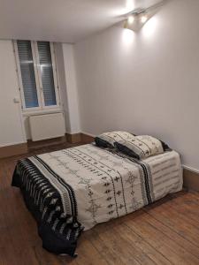 een slaapkamer met een bed met een deken erop bij Autun cœur de ville in Autun