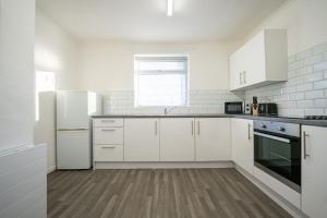 una cocina blanca con armarios y electrodomésticos blancos en Tranmere House Workstays UK Best Rates Direct, en Middlesbrough