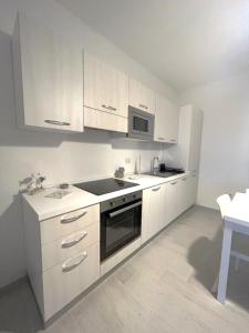 a kitchen with white cabinets and a sink and a microwave at Affittimoderni La Maddalena - MADA14 in La Maddalena