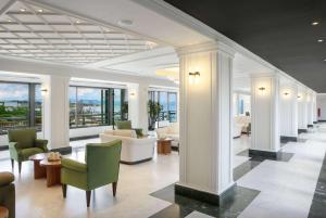a lobby with chairs and tables and windows at Ramada by Wyndham , Athens Club Attica Riviera in Mati