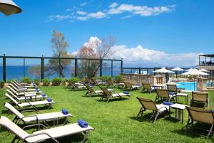a bunch of lawn chairs and lounge chairs on the grass at Ramada by Wyndham , Athens Club Attica Riviera in Mati