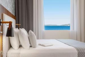een slaapkamer met een bed en uitzicht op de oceaan bij Ramada by Wyndham , Athens Club Attica Riviera in Mati