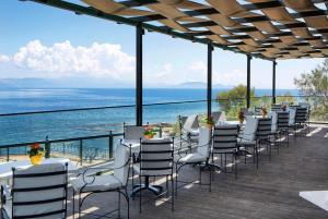 uma fila de cadeiras e mesas num deque com o oceano em Ramada by Wyndham , Athens Club Attica Riviera em Mati
