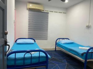 two beds in a hospital room with a window at Hs Homestay Cenderawasih Kuantan Town (5 Bed) in Kuantan