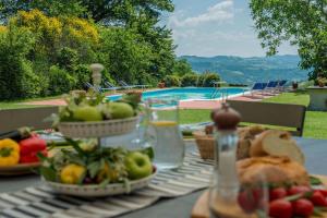 una mesa con frutas y verduras y una piscina en Villa Petroia 8, en Gubbio