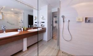 a bathroom with two sinks and a shower at ATLANTIC Hotel Landgut Horn in Bremen