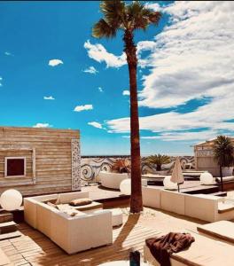 a patio with a palm tree and white furniture at Agde MOBIL HOME 3CH-SECTEUR VIP GARDEN VILLAGE CLUB PARC ACQUATIQUE in Le Grau-dʼAgde