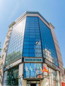 a tall glass building with flags in front of it at Hotel Meridian in Chelyabinsk