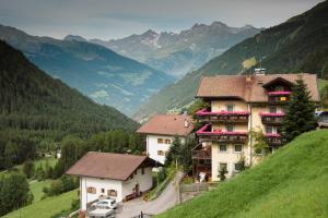 a building on a hill with mountains in the background at Gasthof Innerwalten in San Leonardo in Passiria