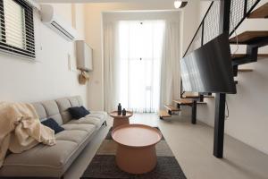 a living room with a couch and a flat screen tv at PORT CITY HAIFA - Urbanic Loft in the Heart of Haifa's Downtown in Haifa