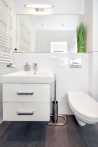 a white bathroom with a toilet and a sink at Orientarium Business Apartments with Parking by Rentujemy in Łódź