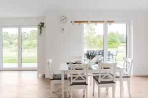 uma sala de jantar branca com uma mesa e cadeiras brancas em Wohnambiente am See em Müden