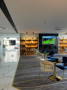 a lobby with tables and chairs and a tv on a wall at فندق ياز in Taif