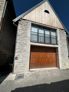 una puerta de garaje de madera con balcón en un edificio en Maison de campagne, en Vuillafans
