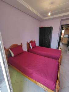twee bedden in een kamer met roze lakens bij Molto carino ben solare in Sidi Rahal