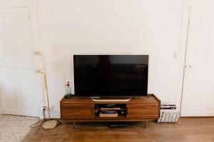 a flat screen tv sitting on top of a wooden entertainment center at Maison avec jacuzzi in Montarmin