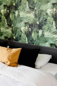 Una cama con 4 almohadas y una pared con plantas. en Maison avec jacuzzi, 