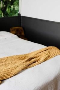 um cobertor castanho numa cama branca com uma janela em Maison avec jacuzzi 