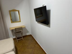 um quarto com uma televisão numa parede com uma mesa em Hostal Rio em Medellín