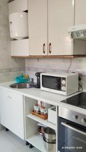 een witte keuken met een wastafel en een magnetron bij Apartamento Agradable1 in Madrid